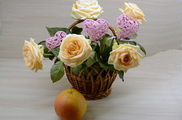 Wall Mural -  On a white background, a basket with fresh pink roses, decorative, openwork hearts, on the table is a grapefruit.