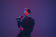 © master1305 - Young caucasian musician, performer singing on gradient purple-blue background in neon light. Concept of music, hobby, festival. Joyful party host, DJ, stand upper, singer. Colorful portrait of artist