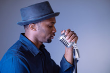 Portrait Of A Hipster Attractive Black Man Singing A Vintage Song. Isolated Male Performing Ethnic Cultural Songs. Young African American Singer Holding Trendy Microphone. Compose And Create Lyrics.