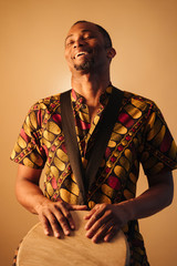 Online musical class learning musical instruments. Rhythm and blues style. Ethnic culture and traditions. African american man musician playing traditional drums at brown background copy space.