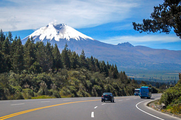 Highway south towards the Cotopaxi volcano, with traveling vehicles, on a sunny morning, Ecuador.