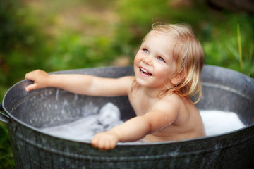  girl bathing in a basin on the street, water splashes, summer in the village, happy childhood, children's laughter