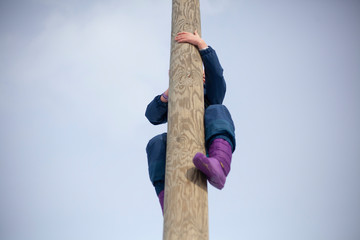 A girl climbs on a pole. Mountain climbing for children.