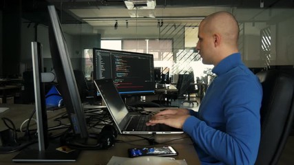 The programmer works at a computer in an empty office during quarantine. Working from home