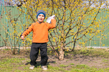 A Small Boy Is Flying A Toy Airplane. He Is Having Fun In The Garden. He Is Happy. Aircraft. Cheap flights. Traveling with children. boy holding paper airplanes. Low cost flights. Avia