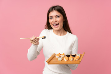 Young girl with sushi over isolated pink background