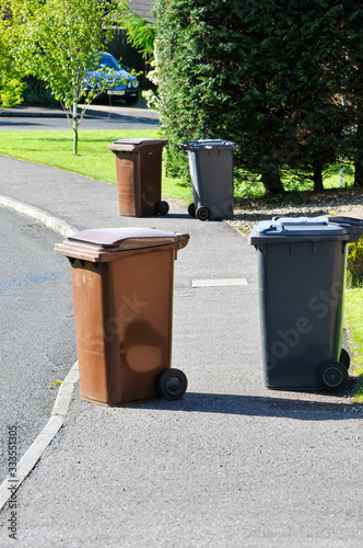 Brown and black recycling wheelie bins spread over a pedestrian footpath