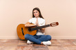 © luismolinero - Young woman with guitar sitting on the floor pleading