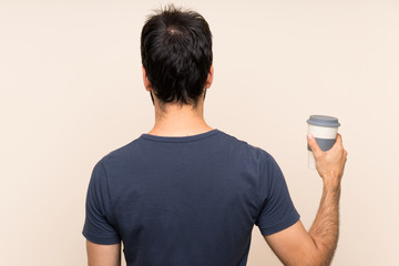 Man with beard holding a coffee in back position