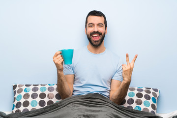 Wall Mural - Man in bed with beard holding a cup of coffee