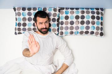 Wall Mural - Man in bed in top view making stop gesture