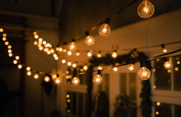 Luminous incandescent lamps hang in the form of a garland on wires, against the background of a shop window. Background from a garland. Incandescent lamps.