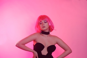 Wall Mural - A gorgeous girl with pink hair in a black fashion dress and a checker in pink. The girl focuses on the chest.