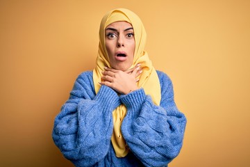 Poster - Young beautiful brunette muslim woman wearing arab hijab over isolated yellow background shouting suffocate because painful strangle. Health problem. Asphyxiate and suicide concept.