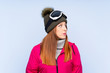 © luismolinero - Skier redhead woman with snowboarding glasses over isolated blue wall looking side