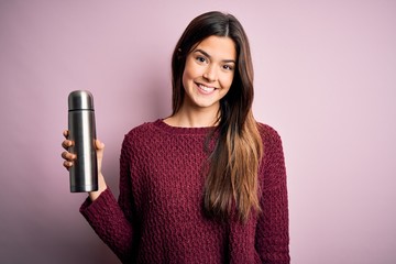 Poster - Young beautiful girl holding thermo with water standing over isolated pink background with a happy face standing and smiling with a confident smile showing teeth