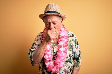 Sticker - Grey haired senior man wearing summer hat and hawaiian lei over yellow background feeling unwell and coughing as symptom for cold or bronchitis. Health care concept.