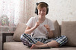 © Oksana - Teenager listens to music on headphones and dances. Boy enjoys music at home