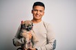 © Krakenimages.com - Young handsome latin man holding cute puppy pet over isolated white background with a happy face standing and smiling with a confident smile showing teeth