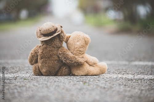 Fotografía One teddy bear with his/her arm wrapped around a smaller teddy bear showing comp