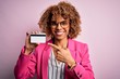 Young african american business woman holding id card identification over pink background very happy pointing with hand and finger