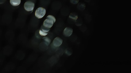 Poster - Close up of rotating blurred party lights of silver color on black background. Concept. Spinning disco ball with shining mirror particles.