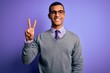 © Krakenimages.com - Handsome african american businessman wearing glasses and tie over purple background smiling with happy face winking at the camera doing victory sign. Number two.