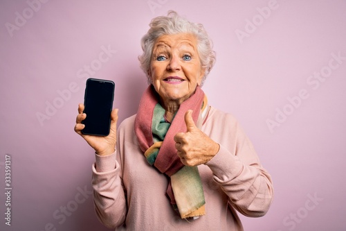 Cuadros en Lienzo Senior beautiful grey-haired woman holding smartphone showing screen over pink b
