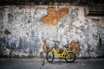 Yellow bicycle parked in front of the old wall