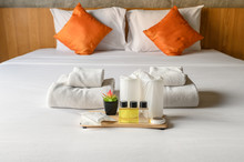Set Of Hotel Amenities (such As Towels, Shampoo, Soap, Drinking Glass Etc) On The Bed. Hotel Amenities Is Something Of A Premium Nature Provided In Addition To The Room When Renting A Room.