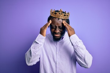 Sticker - Young african american man wearing golden crown of king over isolated purple background with hand on head for pain in head because stress. Suffering migraine.