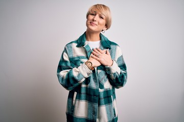 Canvas Print - Young blonde woman with short hair wearing casual retro green shirt over isolated background smiling with hands on chest with closed eyes and grateful gesture on face. Health concept.