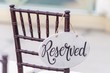 Closeup shot of a reserved sign hanging on a chair at a wedding ceremony