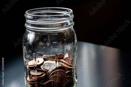 Glass tip jar partly full of loose coin change