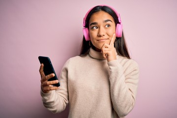 Poster - Young beautiful asian woman listening to music using smartphone and headphones serious face thinking about question, very confused idea