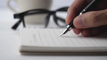 Poster - Male hands with glasses and cup of coffee write pen in a notebook of tasks and goals to work on a white table