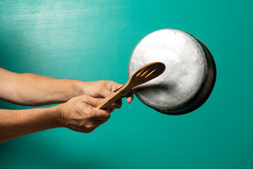 person hitting pot to protest, with a green background.