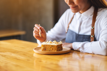 Canvas Print - A female chef baking and eating a piece of homemade carrot cake in wooden tray