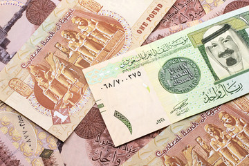 A close up image of a one riyal bank note from Saudi Arabia on a background of Egyptian one pound bank notes in macro