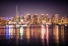 The Lights Of San Diego's Skyline Reflect Off The Waters Of The Pacific Ocean, With Sailboats In The Foreground.
