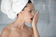 Woman with towel on head put palm in front face opens mouth check breath close up image. Suffers from unpleasant odor due to oral infections, poor dental hygiene, health problems, halitosis concept