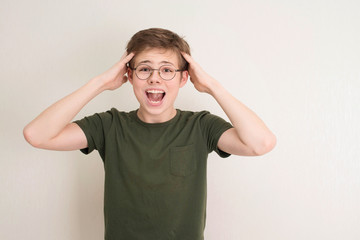 Portrait of surprised teen boy in eyeglasses on white background. Funny boy looking at camera in shock or amazement. Handsome teenager.