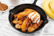 Homemade fried bananas foster with cinnamon and ice cream in cast iron pan