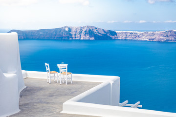  Two chairs on the terrace with sea views. Santorini island, Greece. Travel and vacation background. Best in travel landscape for romantic couple or honeymoon destination. Fantastic location and view