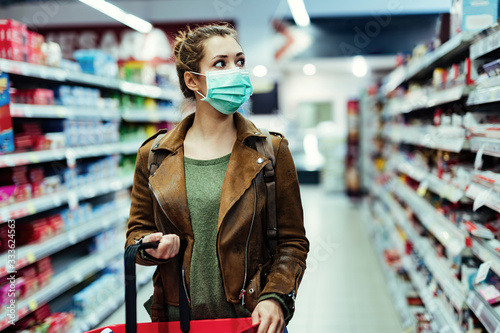 Fotografía Woman wearing face mask while shopping in supermarket during virus pandemic