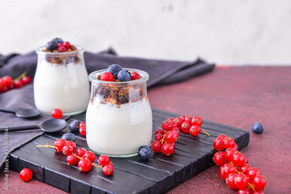 Jar with tasty yogurt, granola and berries on table