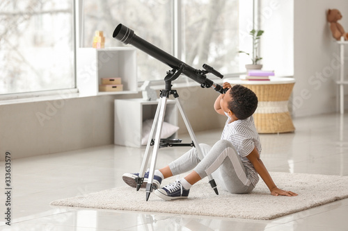 Fotomural Little African-American boy with telescope at home