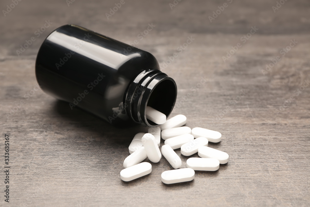 Jar with pills on wooden background