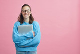 Fototapeta  - Cute looking student holding her laptop beside copy space 