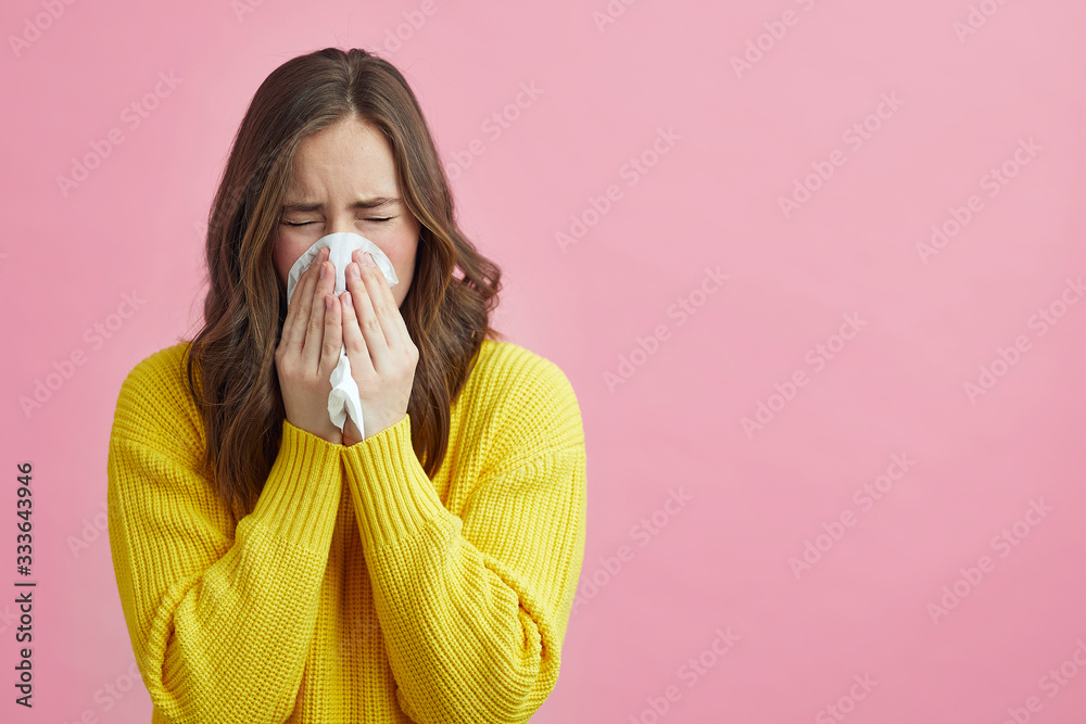 Pretty girl is Sneezing into a tissue because of her allergy or cold  - obrazy, fototapety, plakaty 